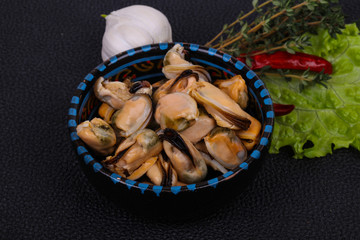 Pickled mussels in the bowl served pepper, garlic and salad