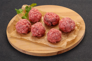 Raw meatball over wooden background