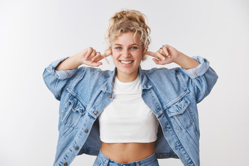 Happy carefree positive playful blond curly-haired woman blue eyes white teeth grinning close ears put index fingers holes unhear unwilling hear friend talking fool around, have fun white background - Powered by Adobe