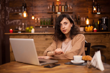 Fototapeta premium Attractive caucasian woman using her laptop in a coffee shop with interent connection