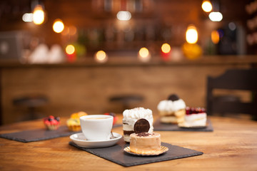Various slices of delicious cakes on a wooden table in a coffee shop