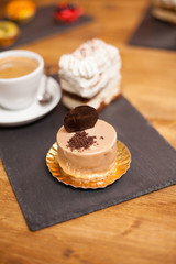 Delicious cake with brown glaze and delicious biscuit on top over a wooden table in a coffee shop