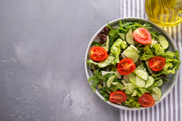Fresh mix of salads with cucumbers and  fresh tomatoes on a plate. Healthy and diet food. Top view.  Copy space