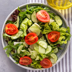 Fresh mix of salads with cucumbers and  fresh tomatoes on a plate. Top view.  Closeup