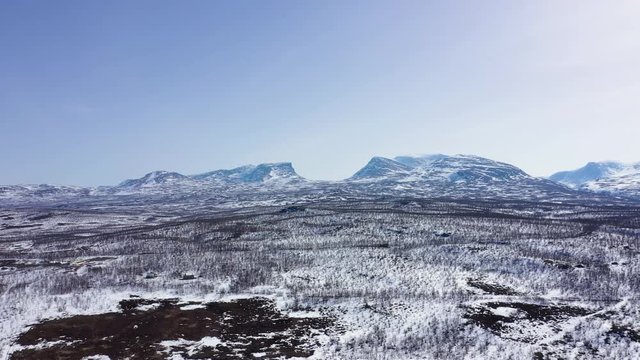 Aerial view of Swedish mountains and the Lapponian gate. Snowy landscape and blue sky. MOVING FORWARD.