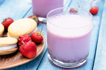 Cocktail with milk and berries club in a glass against the background of blue boards.