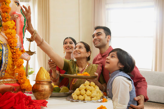 Family perfoming Ganpati aarti on Ganesh Chaturthi at home	