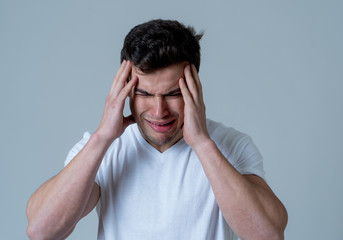 Portrait of sad young man in strong emotional pain having headache and migraines