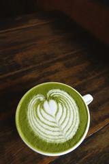 A cup of green tea matcha latte on wooden background
