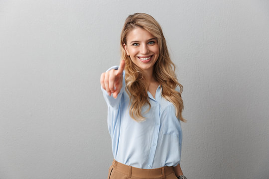 Photo of charming blond businesswoman with long curly hair smiling and pointing fingers at you