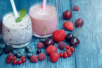 Raspberry, strawberry and blueberry smoothie on blue wooden background. milkshake with fresh berries. berry yogurt with blueberries, raspberries and blackberries. summer healthy vegetarian Breakfast.