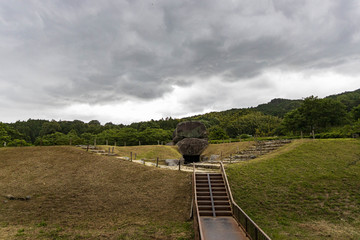 Dramatic storm clouds over large stones marking ancient tomb in Asuka, Japan