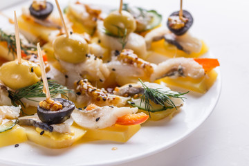 Salted herring on skewers with cheese and olives on plate