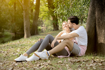 Portrait of a man kiss girlfriend under tree in park