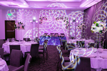 Wedding banquet in blue and white tones. Beautiful table setting with crockery and white flower arrangements in a vase on a high stem for a party, wedding reception or other festive event