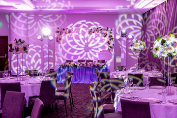 Wedding banquet in blue and white tones. Beautiful table setting with crockery and white flower arrangements in a vase on a high stem for a party, wedding reception or other festive event