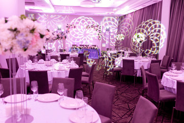 Wedding banquet in blue and white tones. Beautiful table setting with crockery and white flower arrangements in a vase on a high stem for a party, wedding reception or other festive event