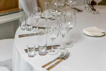 Beautiful table setting with crockery for a party, wedding reception or other festive event. Empty glassware and cutlery for catered event dinner. Horizontal photo