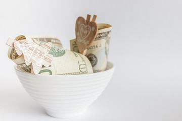 American dollars with decorative clothes pins in the ceramic bowl
