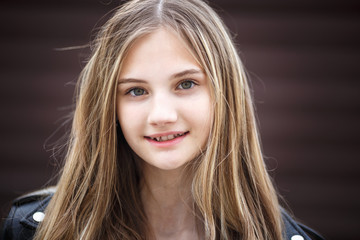 close-up portrait of little beautiful stylish kid girl against a brown striped wall