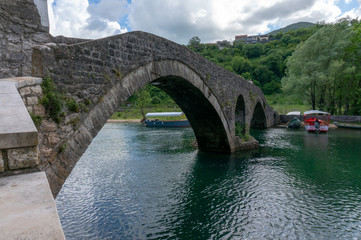 Fototapeta na wymiar view to old bridge in the village Rijeka Crnojevica reflecting in the water in Montenegro. Stari most.