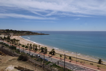 Fototapeta na wymiar Bord de mer avec plage de sable; route; palmiers et ciel bleu.