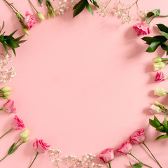 Obraz na płótnie Canvas Wreath made of eustoma and gypsophila flowers on pink pastel background
