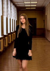 A young girl stands in the middle of a long corridor