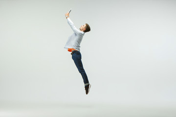 Happy young man working at office, jumping and dancing in casual clothes or suit isolated on white...