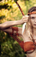 Beautiful girl archer with long blond hair with bow and arrowson a back holding two steel knifes...