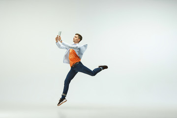 Fototapeta na wymiar Happy young man working at office, jumping and dancing in casual clothes or suit isolated on white studio background. Business, start-up, working open-space, ballet or professional occupation concept.