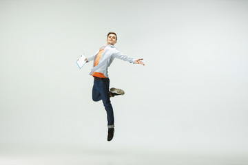 Happy young man working at office, jumping and dancing in casual clothes or suit isolated on white...