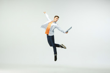 Happy young man working at office, jumping and dancing in casual clothes or suit isolated on white studio background. Business, start-up, working open-space, ballet or professional occupation concept.