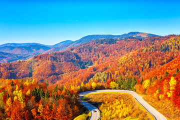 Scenic alpine winding road in autumn mountains with colorful trees and blue sky, outdoor travel background, Narodny park Slovensky Raj (National park Slovak paradise), Slovakia (Slovensko)