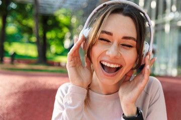 Fitness sports woman posing outdoors in park listening music