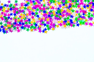 Many multicolored confetti stars on a white background.