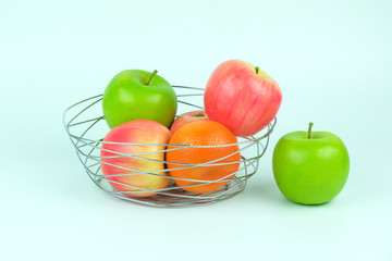 Apples and oranges in a decoratively wire basket put on isolated white background and there is an apple outside the wire basket with clipping path.