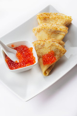 Pancakes with a red caviar stuffing. White background. Close up. Selective focus.