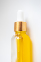 Close-up oil serum essence in glass bottle on white background. Macro skincare product vertical photo