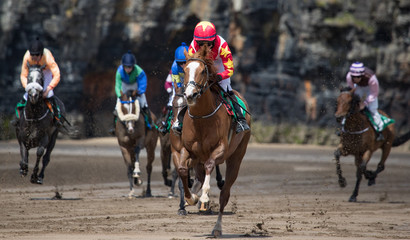 Horse racing action on the beach, focus on lead race horse and jockey