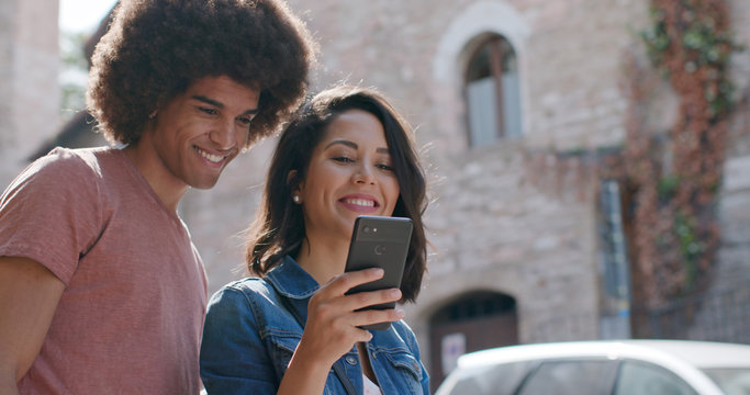 Fototapeta Romantic couple using smartphone to search amenities or landmarks in rural town of Assisi.Portrait medium shot.Friends italian trip in Umbria.4k slow motion