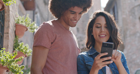 Romantic couple using smartphone to search amenities or landmarks in rural town of Assisi.Portrait...
