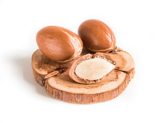 Moroccan argan nuts on wood background close-up isolated white. Argania spinosa seeds.