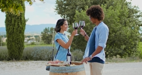 Romantic couple, man and woman toasting with red wine and eating appetizer at warm sunset.Medium...