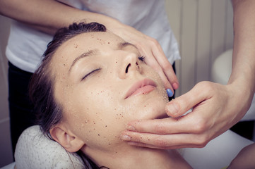 Fototapeta premium Cosmetician applying facial mask at young woman in spa salon