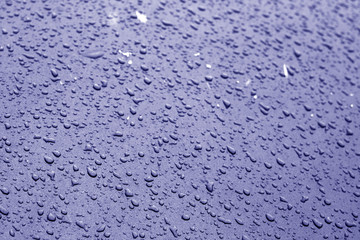 Water drops on car surface in blue tone.