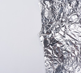 ragged edge of silver foil on a white background, close up