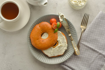 Breakfast with bagels and cheese, cherry, basil, tea cup. Healthy food.