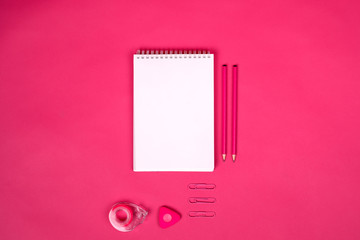 White notebook with different school  colorful supplies on pink background. Back to school