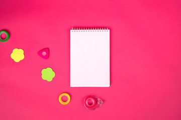 White notebook with different school  colorful supplies on pink background. Back to school